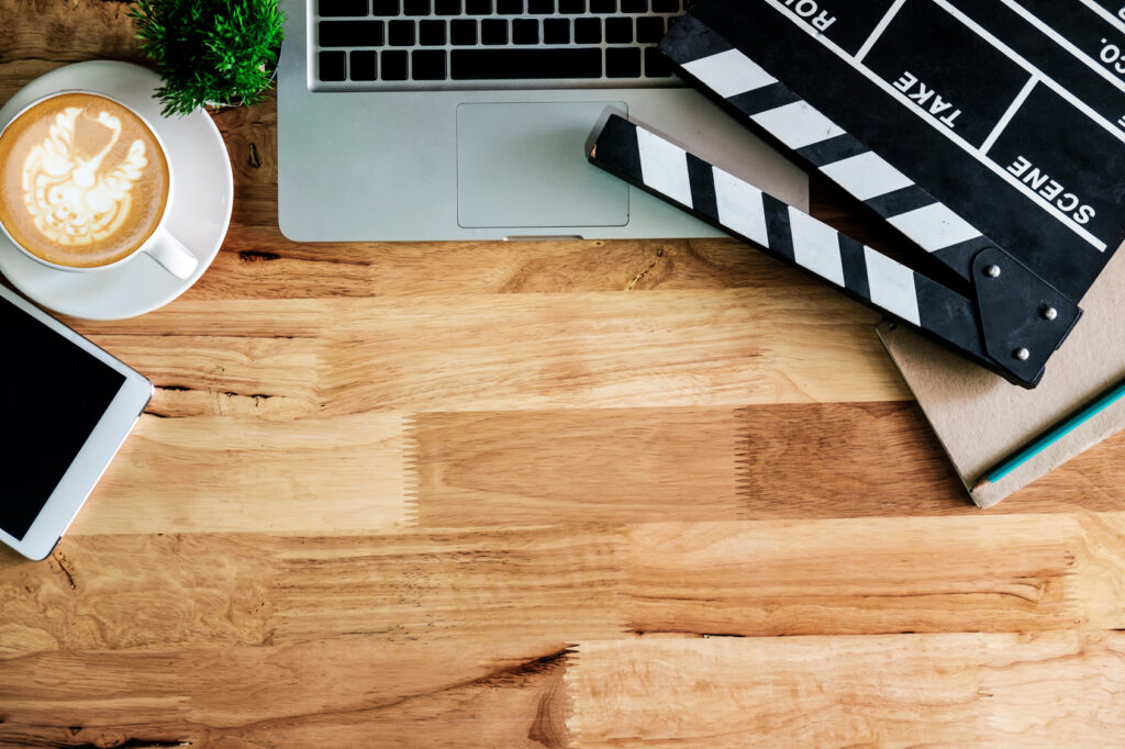 Desk with a clapperboard, laptop, notepad and coffee