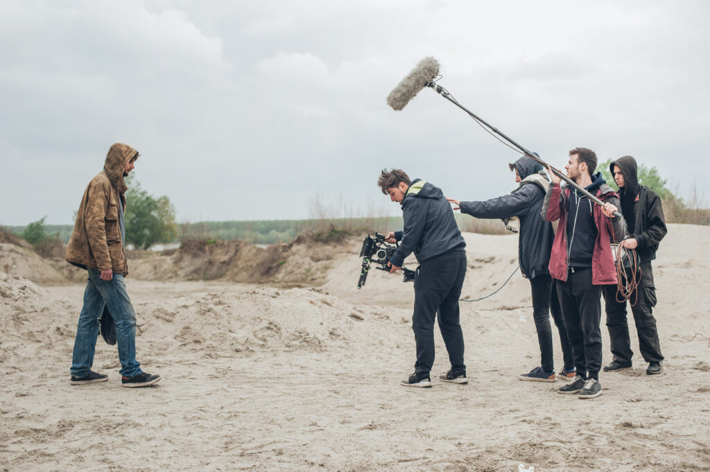 Film crew with a boom microphone shooting outdoors